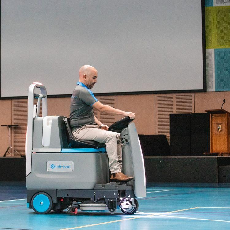 Man with i-drive ride-on floor scrubber